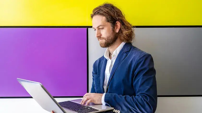 A man in a suit is focused on his laptop, engaged in work or a professional task