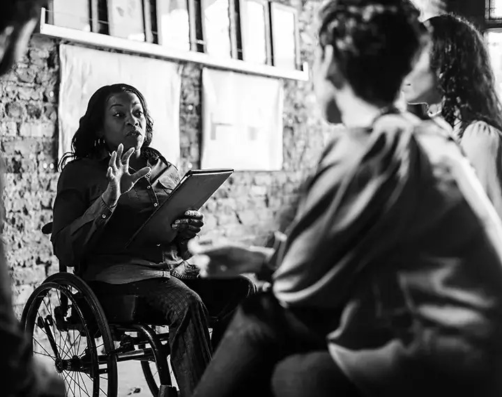 A woman in a wheelchair engages in conversation with a diverse group of people, fostering an inclusive dialogue.
